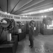 stoisko w formie czterech prostopadłościanów, na których postawiono silniki lotnicze, przed nimi stoi dwóch mężczyzn