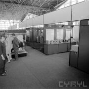 stoiska w hali wystawowej, zwiedzający ludzie z lewej