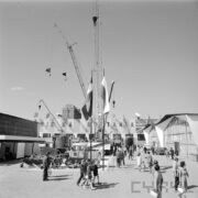 stoiska ze spychaczami na betonowym placu, otoczonym budynkami, zwiedzający ludzie