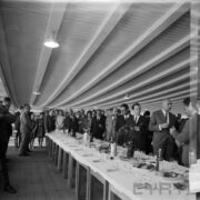 duża grupa kobiet i mężczyzn stojących przy zastawionym stole w hali wystawowej