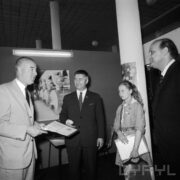 trzech mężczyzn, jeden z nich trzyma w rękach dyplom, druga z prawej dziewczynka w stroju harcerki