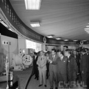 grupa mężczyzn ogląda stoiska z urządzeniami w hali wystawowej