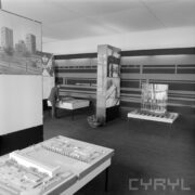 stoisko w hali wystawowej, w głębi nachylony nad gablotą mężczyzna