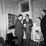 trzech mężczyzn, jeden z nich podaje drugiemu dyplom, druga z prawej dziewczynka w stroju harcerki