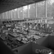 stoiska w hali wystawowej, u góry hali duże okna ciągnące się przez całą długość budynku