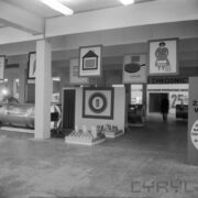 stoisko w hali wystawowej z ekspozycją margaryn i olejów, plakaty reklamowe podwieszone do sufitu