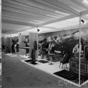 stoiska z ubranymi manekinami w pawilonie wystawowym, w głębi na ścianie zdjęcie gór