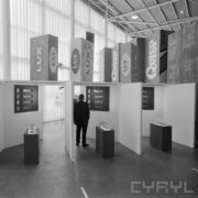 stoiska w hali wystawowej, pomiędzy nimi zwiedzający ludzie