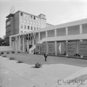 budynek otynkowany, nad wejściem wiszą flagi państw, z prawej tablice informacyjne