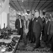 grupa mężczyzn ogląda stoisko z butami w pawilonie wystawowym