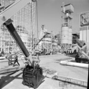 stoisko z rusztowaniami, obok silosy, wystawie przyglądają się mężczyźni