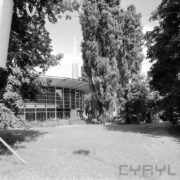 okrągły, przeszklony budynek w otoczeniu drzew