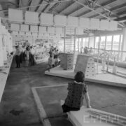 stoisko z przyrządami do ćwiczeń sportowych, sprzęt turystyczny w budynku ze skośnym dachem, zwiedzający ludzie