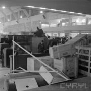 z przodu drewniane skrzynie, za nimi maszyny w hali targowej