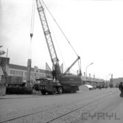 ulica na terenie targów, środkiem biegną tory kolejowe, w głębi samochód z dźwigiem