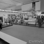 stoisko z maszynami i urządzeniami w hali wystawowej, zwiedzający ludzie