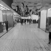 stoisko w hali wystawowej, zwiedzający ludzie, u sufitu wiszą okrągłe reklamy firm