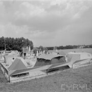 rozłożone namioty na trawie, z lewej drzewa, z prawej w oddali jezioro