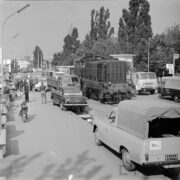 ulica na terenie targów, samochody osobowe i dostawcze, w środku lokomotywa spalinowa, z lewej grupa mężczyzn