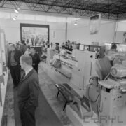 stoiska w pawilonie wystawowym, pomiędzy nimi zwiedzający ludzie