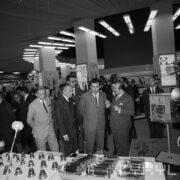 grupa mężczyzn ogląda stoiska z urządzeniami w hali wystawowej