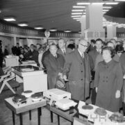 duża grupa ludzi w płaszczach w hali wystawowej