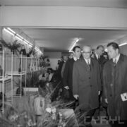 grupa mężczyzn, część w płaszczach w hali wystawowej