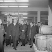 grupa mężczyzn w płaszczach w hali wystawowej