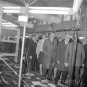 grupa ludzi w płaszczach w hali wystawowej