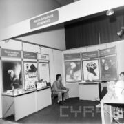 stoisko z urządzeniami w hali wystawowej, w głębi na fotelu siedzi mężczyzna