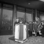 mężczyzna przemawia na mównicy, w głębi grupa ludzi