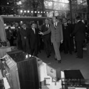 grupa mężczyzn ogląda stoiska wystawowe w przeszklonej hali