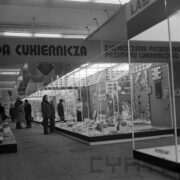 stoiska w hali wystawowej, między nimi zwiedzający ludzie