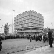 duży plac, na nim tłum ludzi, większość mężczyzn, w głębi kilkupiętrowy budynek, na balkonie, na pierwszym piętrze stoją ludzie