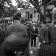 grupa mężczyzn na terenie targów, z prawej kilku starszych mężczyzn w mundurach