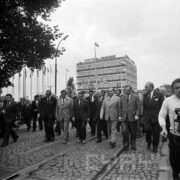 duża grupa ludzi na terenach wystawowych, w głębi kilkupiętrowy budynek targowy