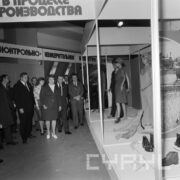 grupa ludzi ogląda stoisko z odzieżą roboczą w hali wystawowej