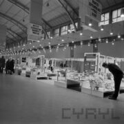 stoiska w hali wystawowej, przy nich stoją ludzie i oglądają ekspozycję