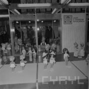 stoisko z lalkami dla dzieci, w głębi zwiedzający ekspozycję ludzie