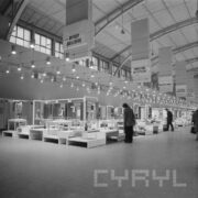 stoiska w hali wystawowej, przy nich stoją ludzie i oglądają ekspozycję