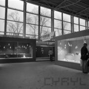 stoiska w hali wystawowej, przy nich oglądający ekspozycję ludzie