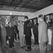 grupa mężczyzn w pawilonie wystawienniczym, pośrodku dwóch mężczyzn podaje sobie dłonie