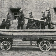 ponton na wozie ciągniętym przez dwa konie; u góry sześciu mężczyzn ubranych w mundury i hełmy strażackie