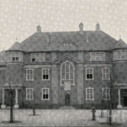 duży budynek z cegieł, przed budynkiem widoczne świeżo posadzone drzewa