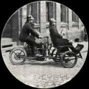 dwóch mężczyzn w mundurach i hełmach strażackich jadących na specjalnym wózku strażackim