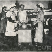 troje młodych dziewcząt z nauczycielką stojących przy kuchni; widoczny sprzęt gospodarstwa domowego: garnki, kubki, czajnik